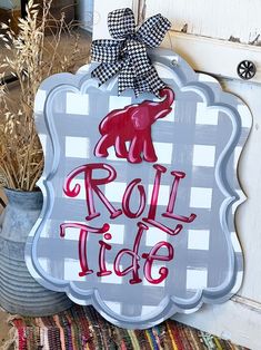 a metal sign that says roll tide on the side of a door with a potted plant next to it