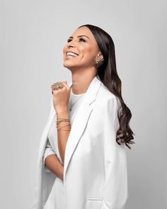 a woman wearing a white suit and gold earrings