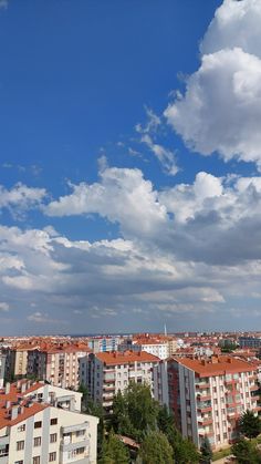 the sky is filled with clouds over some buildings and trees in front of blue skies