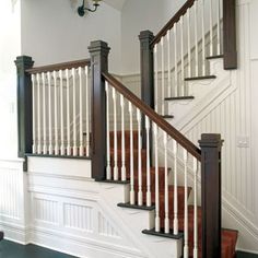 a white staircase with wooden handrails and black railing on the bottom floor in a house