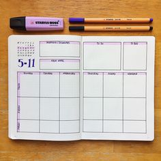 an open planner and two pencils on a wooden table