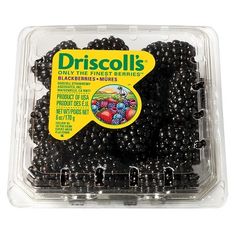 a plastic container filled with blackberries on top of a white surface