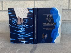 the book of mormon is on display in front of a brick wall with water flowing from it