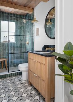 a bathroom with green tiled walls and wood trim on the ceiling, along with a wooden vanity