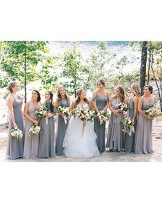 a group of women standing next to each other in front of trees and flowers on the ground