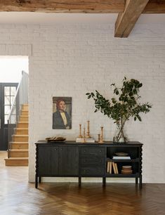 a white brick wall and wooden floor in a living room with stairs leading up to the second floor