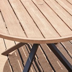 a round wooden table sitting on top of a wooden floor next to a metal chair