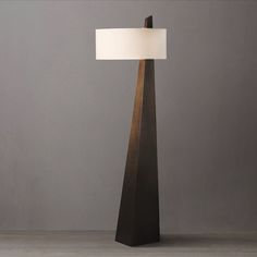 a lamp that is sitting on top of a wooden table next to a gray wall