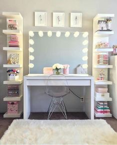 a white desk with a mirror and lights on top of it in front of shelves