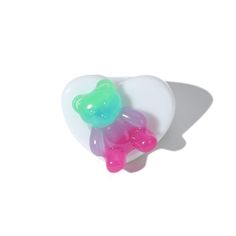 two gummy bears sitting on top of a white heart shaped object in the shape of a bear