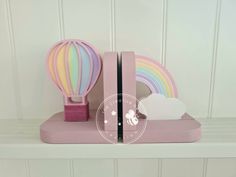 a pink bookend with a rainbow hot air balloon on it and a cloud in the background