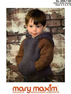 a young boy is wearing a sweater and standing in front of a brick wall with his hands on his hips