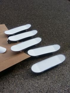 five skateboards laying on the ground next to a cardboard box