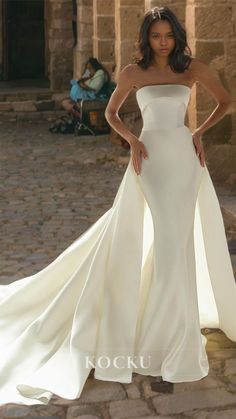 a woman in a white wedding dress posing for the camera with her hands on her hips