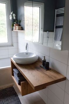 a bathroom sink sitting under a window next to a bathtub and shower head mounted on a wall