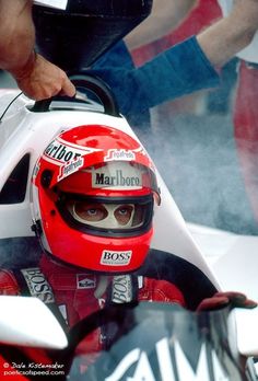 a man sitting in a racing car with his helmet on