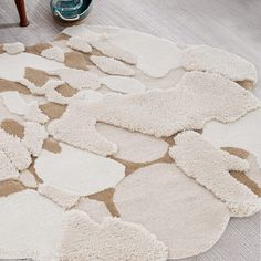 a white rug with brown and beige shapes on the floor in front of a chair