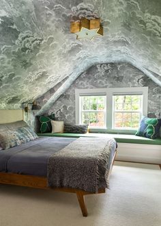 a bed sitting under a window in a bedroom next to a wall papered ceiling