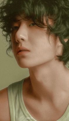 a close up of a person wearing a green tank top and hair in the wind