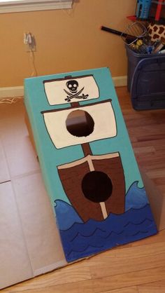 a cardboard box sitting on the floor with a pirate ship painted on it's side