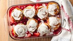 a glass dish filled with pastries covered in icing and strawberries on top of a wooden table