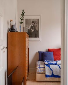 a bedroom with a bed, dresser and pictures on the wall