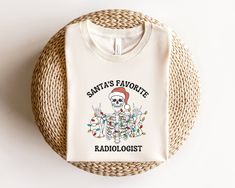 a white t - shirt with santa's favorite radiologist on it sitting next to a wicker basket