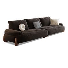 a brown couch with pillows on it sitting in front of a white wall and floor