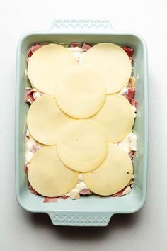 a blue dish filled with cheese and ham