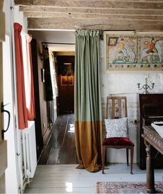 a room with a chair, rug and paintings on the wall