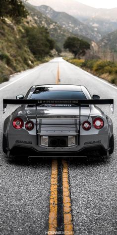 a car parked on the side of a road with mountains in the backgroud