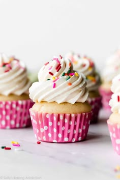 several cupcakes with white frosting and sprinkles