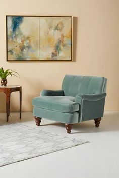 a living room with two chairs and a painting on the wall above it, along with a rug