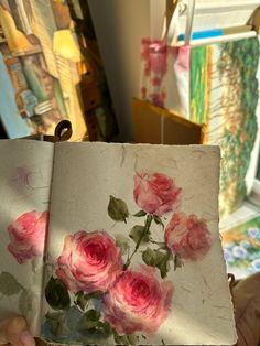 an open book with pink roses painted on it