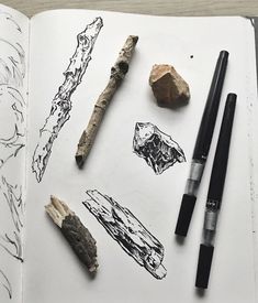 an open book with various types of rocks and pens on it, including pencils