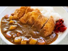 a white plate topped with meat and gravy covered in gravy next to rice