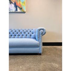 a blue couch sitting in front of a painting on the wall next to a floor