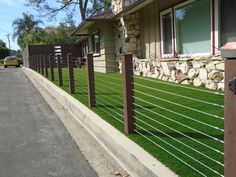 a house with grass growing on the side of it and a fence in front of it