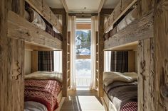 bunk beds are lined up in a room with snow on the windowsill and wooden walls