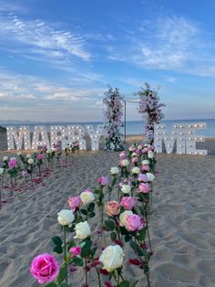 flowers are placed in the sand near an illuminated sign that says marry me on the beach