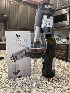 a glass of wine next to a bottle of wine and a corkscrew on a counter top