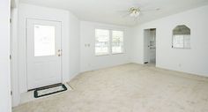 an empty living room with white walls, carpet and ceiling fan in the middle of the room