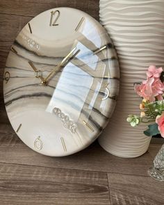 a white clock sitting on top of a wooden table next to vases and flowers