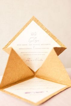 an origami style wedding card with gold foil