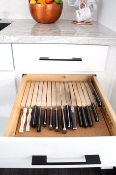 an open drawer with knives and fruit in it