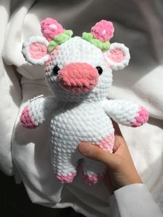 a hand holding a small crocheted stuffed animal in the shape of a cow