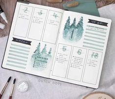 an open planner with watercolor trees on it and some other items next to it