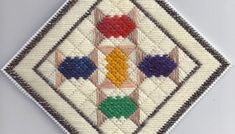 an embroidered patch with different colors and shapes on it's side, in the shape of a diamond