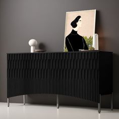 an art piece is on top of a black sideboard in a room with gray walls