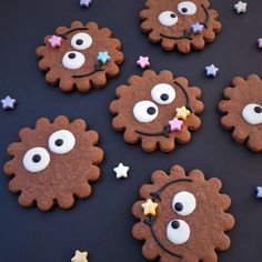 cookies decorated to look like lions with eyes and stars around them on a black surface